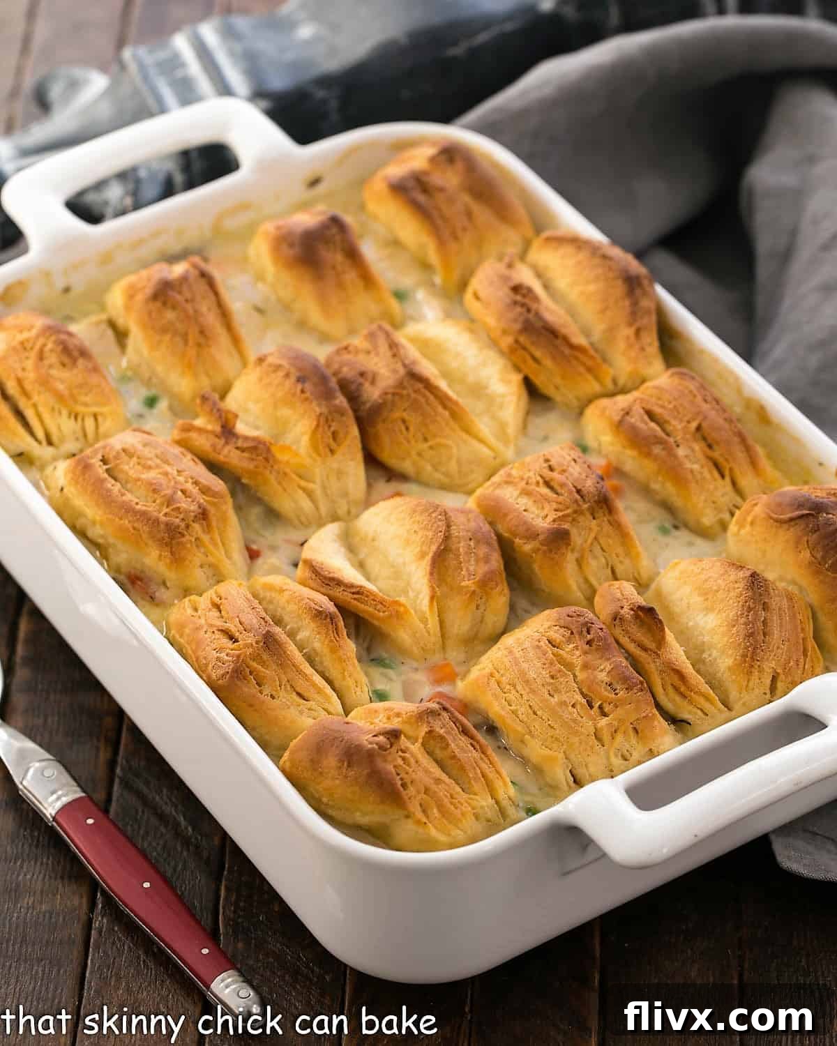 Chicken Pot Pie in a whiite casserole dish topped with butterflake biscuits.