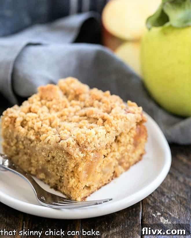 A slice of Apple Streusel Coffee Cake on a small white plate, showing the layers of moist cake, caramelized apples, and streusel topping.