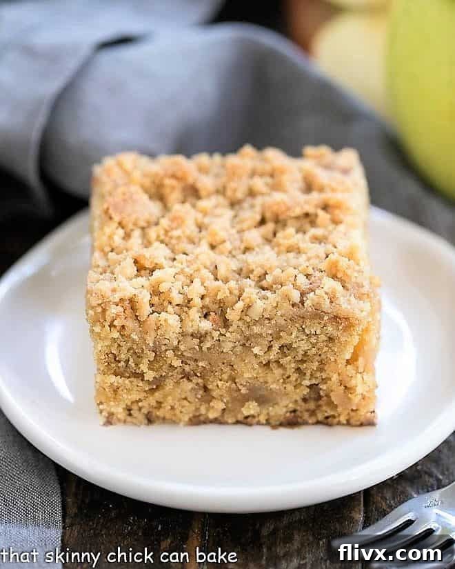 A perfectly baked slice of Apple Streusel Coffee Cake on a white ceramic plate, ready to be enjoyed.