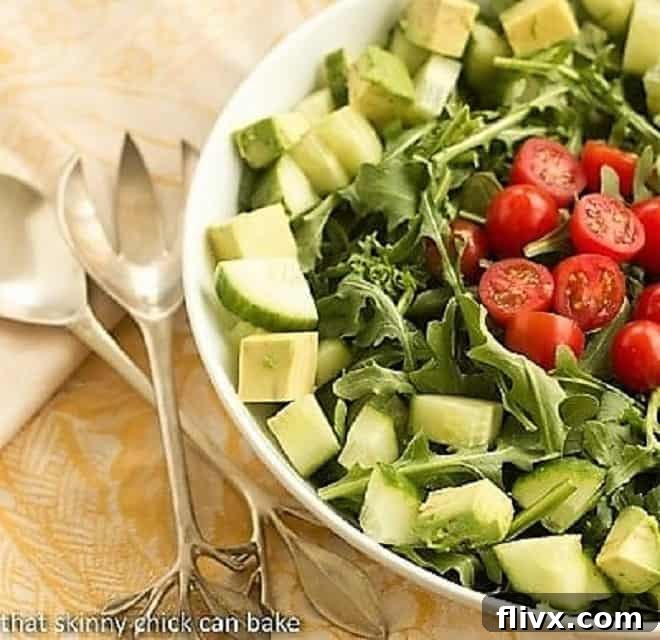 Maddy's Arugula Salad - Fresh produce tossed in a light vinaigrette makes or a fabulous, healthy side dish! Maddy's Arugula Salad in a white ceramic serving bowl, showcasing fresh ingredients and a light dressing.