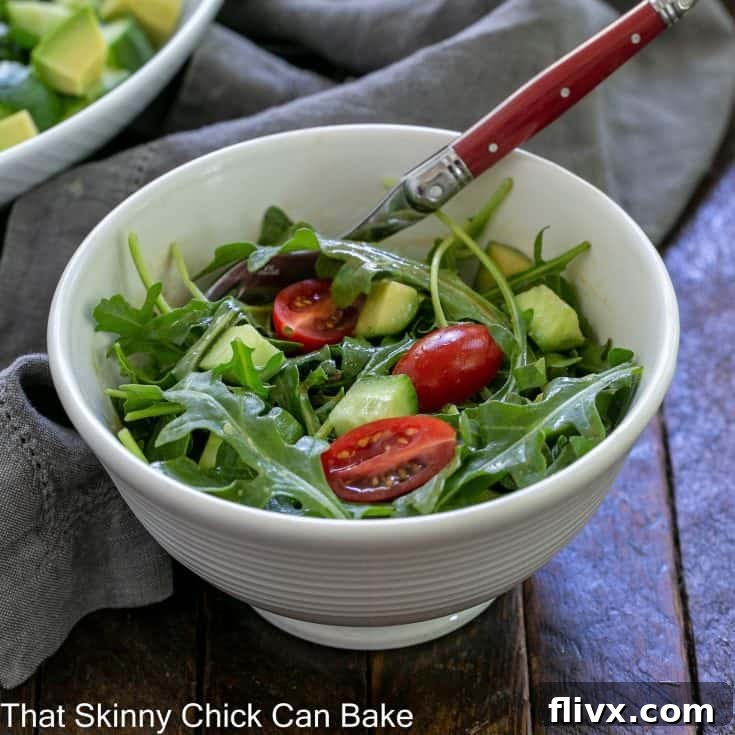 Simple arugula salad in a small white bowl with a fork, ready to be enjoyed.