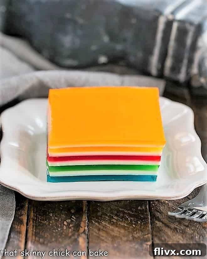 A perfectly cut square of Jello Rainbow Ribbon Salad on a square white plate, showing the distinct layers.