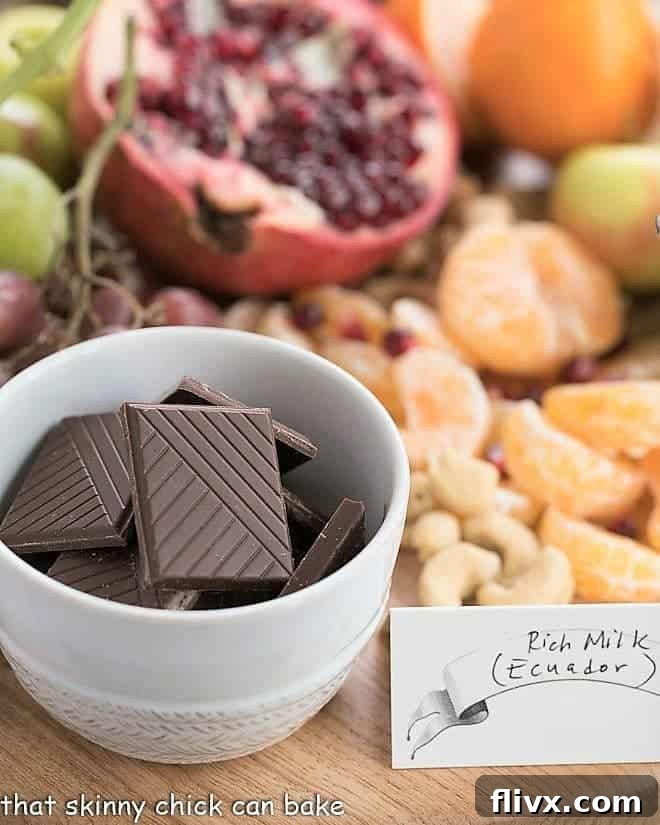 Chocolate Dessert Board with a white bowl of chocolate squares, fruit and nuts A display of various Cémoi chocolate bars arranged neatly beside a luxurious Chocolate Dessert Board, showcasing the premium quality of the French chocolates.