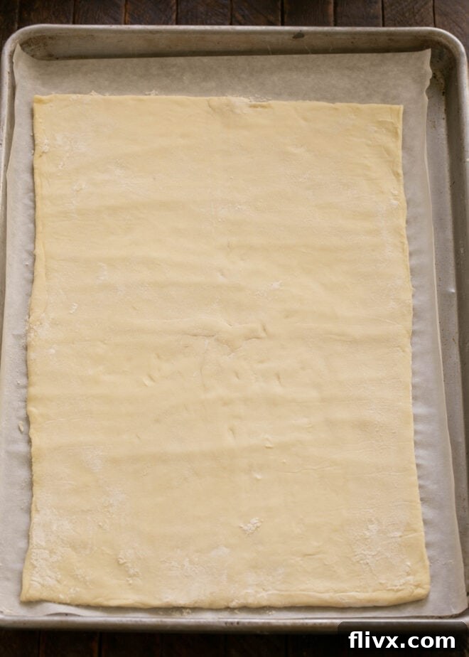 Step 1: Raw puff pastry sheet on a baking pan, ready for apple arrangement.
