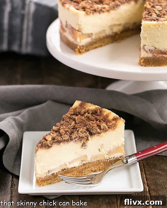 A tantalizing slice of Apple Crisp Cheesecake artfully placed in front of a rustic cake stand, showcasing its intricate layers and inviting texture. The golden brown streusel topping is perfectly crisp, contrasting with the creamy white cheesecake and vibrant apple filling.