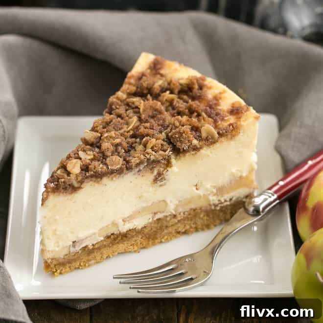 A delicious slice of apple crisp cheesecake displayed on a square white plate, with a background of the full cheesecake.
