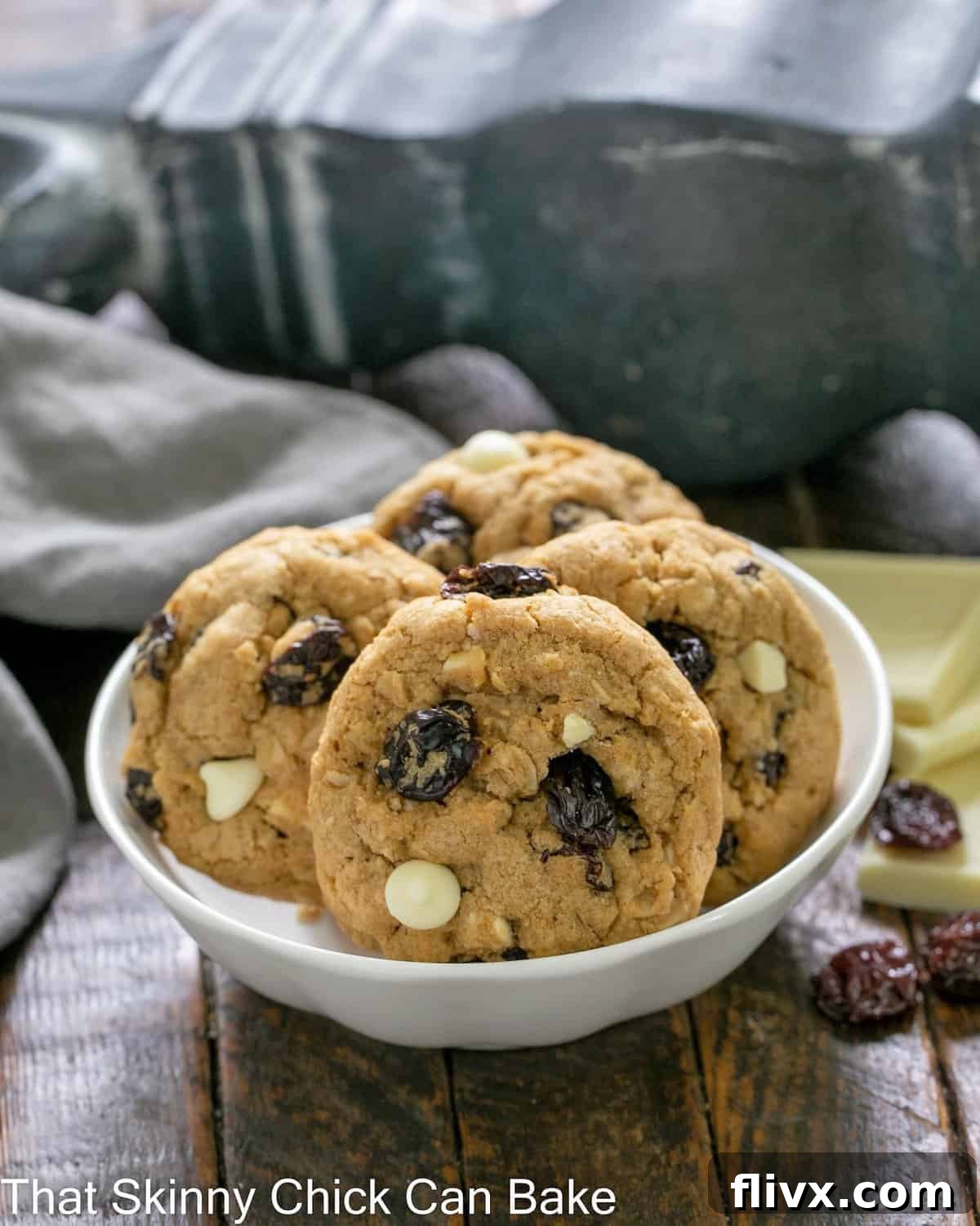 A small white bowl filled with freshly baked Oatmeal, Dried Cherry and White Chocolate Cookies, showcasing their delightful texture.