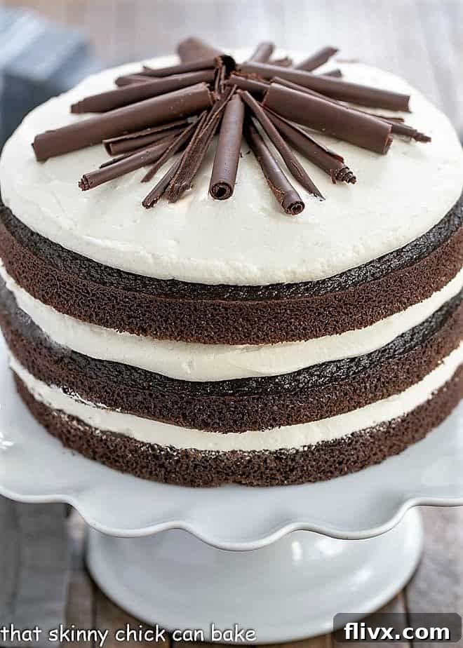 Slice of Triple Layer Chocolate Cake on a white ceramic cake stand, showing the moist layers and creamy frosting.