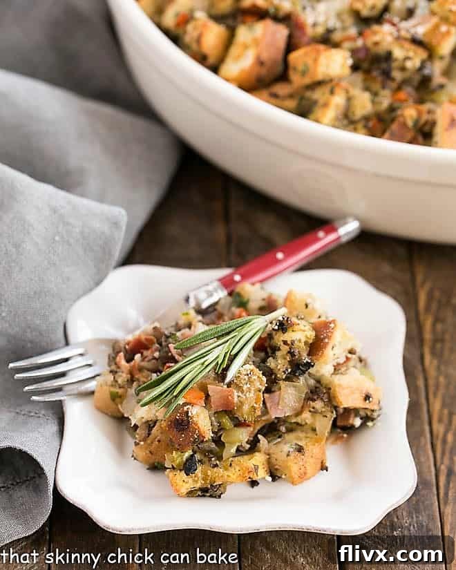 Pancetta Ciabatta Dressing - The BEST stuffing cooked outside of a turkey with an Italian twist! A small plate featuring a generous serving of golden-brown Pancetta Ciabatta Dressing, accompanied by a fork with a red handle.
