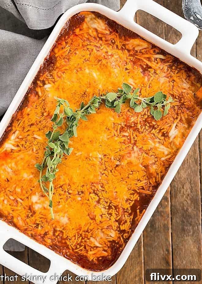 Turkey Enchilada Casserole in a white casserole dish with a sprig of oregano, ready to serve.