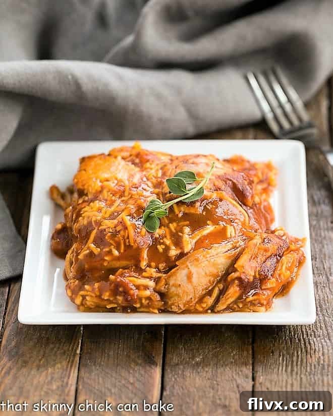 Turkey Enchilada Casserole on a square white plate, garnished with fresh herbs.