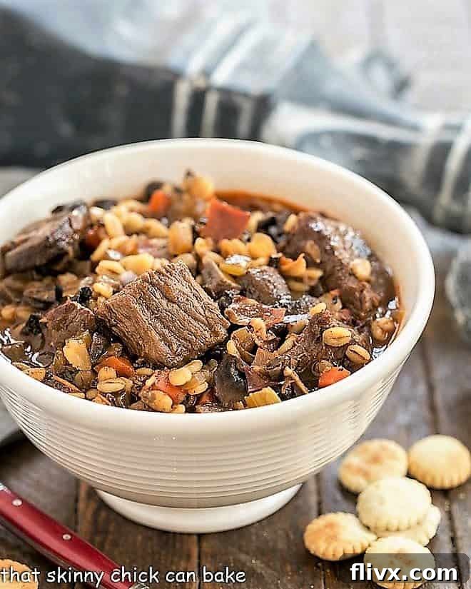 Beef Mushroom Soup with Barley in a rustic soup bowl, garnished with fresh herbs and served with a side of oyster crackers.