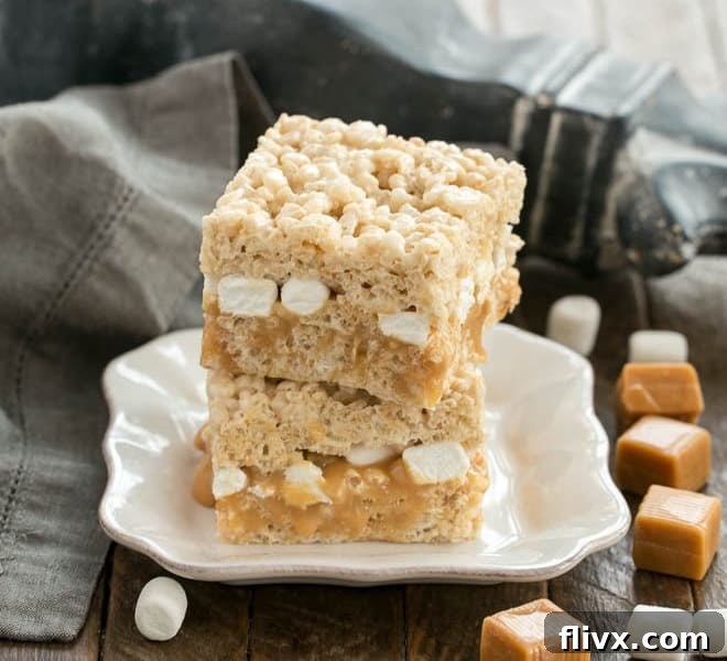 A stack of three Caramel Stuffed Rice Krispie Treats on a square white plate, showcasing the thick caramel layer.