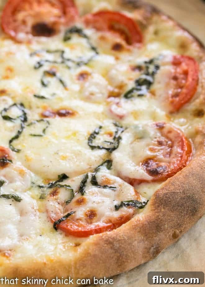 Close view of homemade pizza dough on a sheet of parchment, ready to be shaped and topped.