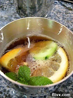 Pimm's Cup in a pewter cup with citrus, mint and cucumber garnish.