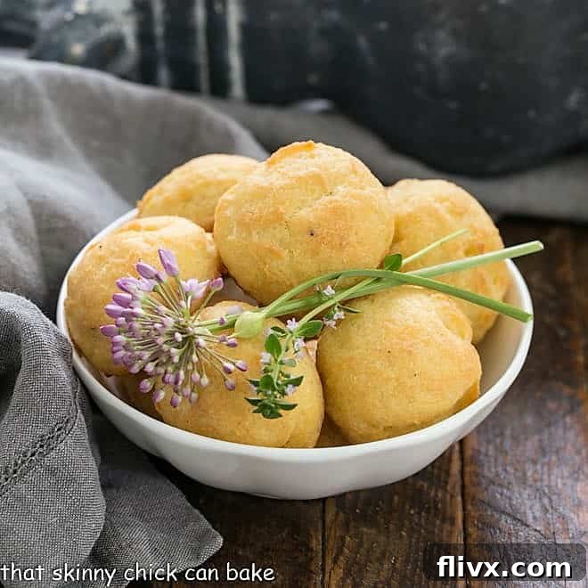 Bowl of cheese puff with chive and thyme garnishes, an inviting display of Gougères, fresh from the oven.
