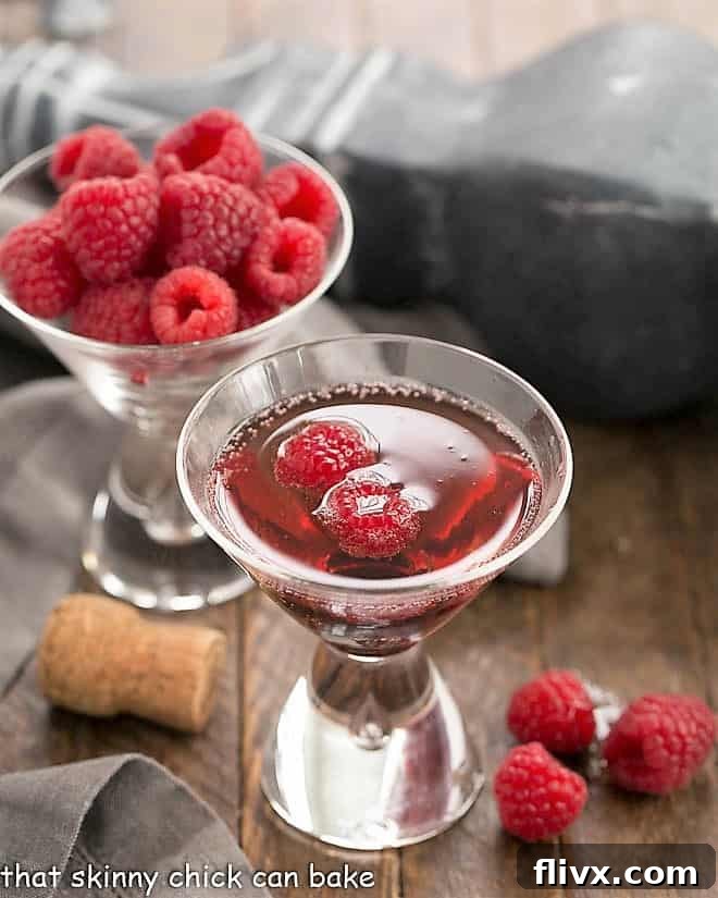Classic Kir Royale with Crème de Cassis served in a elegant champagne flute, garnished with fresh raspberries, against a soft, inviting background.