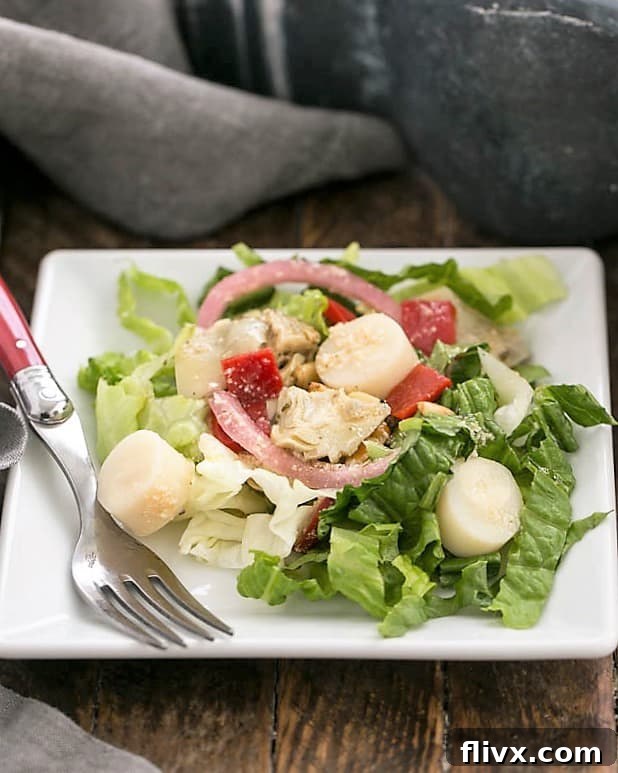 A close-up shot of the Italian Chopped Salad, beautifully arranged on a square plate with a fork, emphasizing its delightful texture and fresh ingredients, ready to be enjoyed.