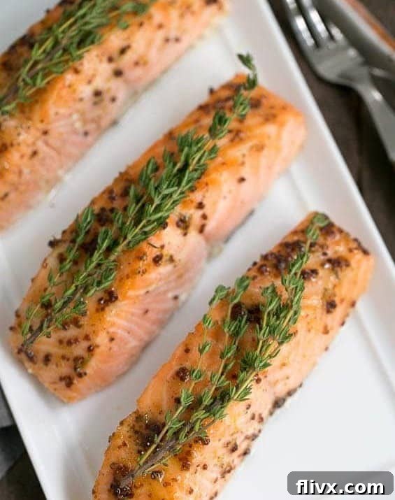 Sweet and Tangy Maple Mustard Salmon 6 Cooked Maple Mustard Glazed Salmon fillets beautifully arranged on a serving tray, garnished with fresh thyme.