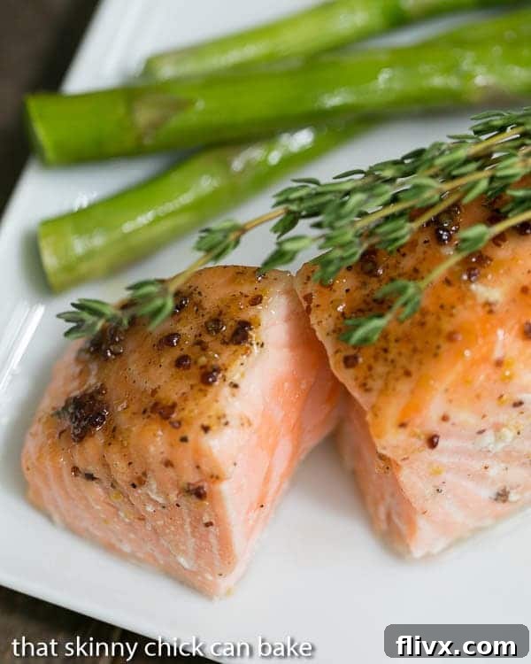 Maple Mustard Glazed Salmon - A super easy glaze, then 15 minutes in the oven for a terrific entree! A close-up of a perfectly cooked Maple Mustard Glazed Salmon fillet on a white plate, showing the flaky, moist interior, garnished with fresh thyme.