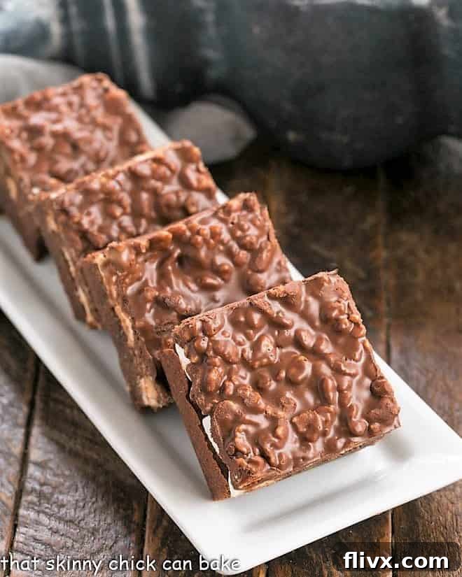Decadent Peanut Butter Krispie Topped Brownies arranged artfully on a pristine white platter, showcasing their delicious layers and enticing texture.