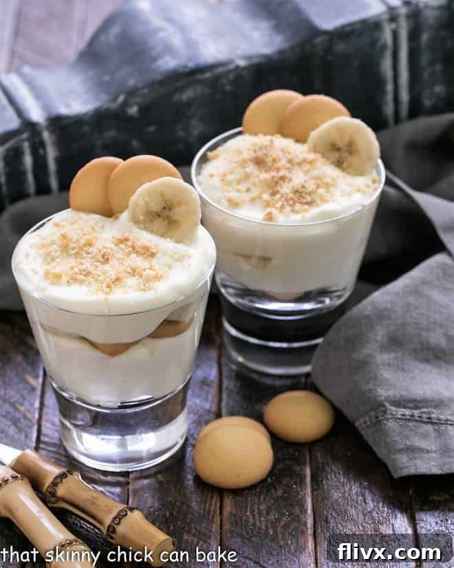 Two clear glasses showcasing layers of Old-Fashioned Southern Banana Pudding, garnished with whipped cream and a vanilla wafer.