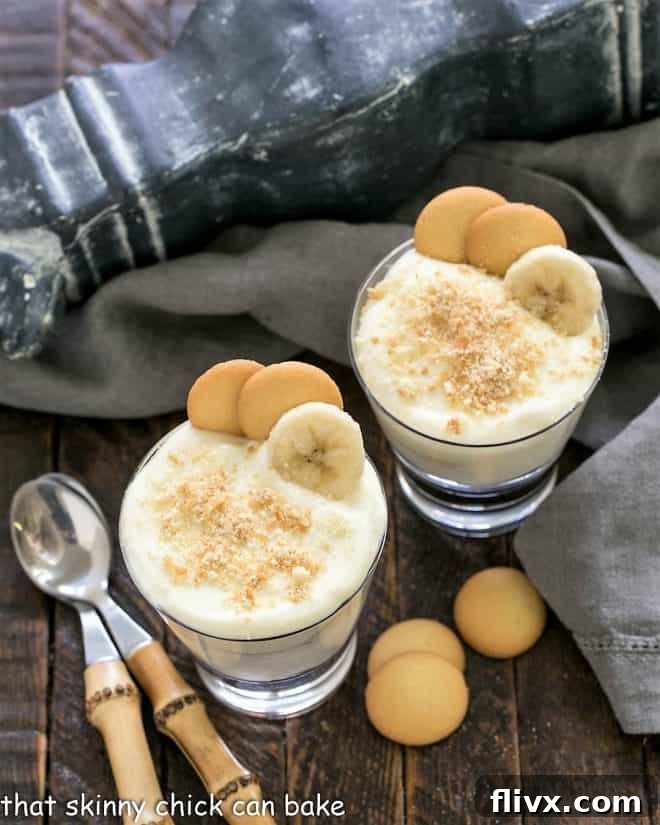 Overhead view of two perfectly layered banana pudding parfaits, each with a spoon, ready to be enjoyed.
