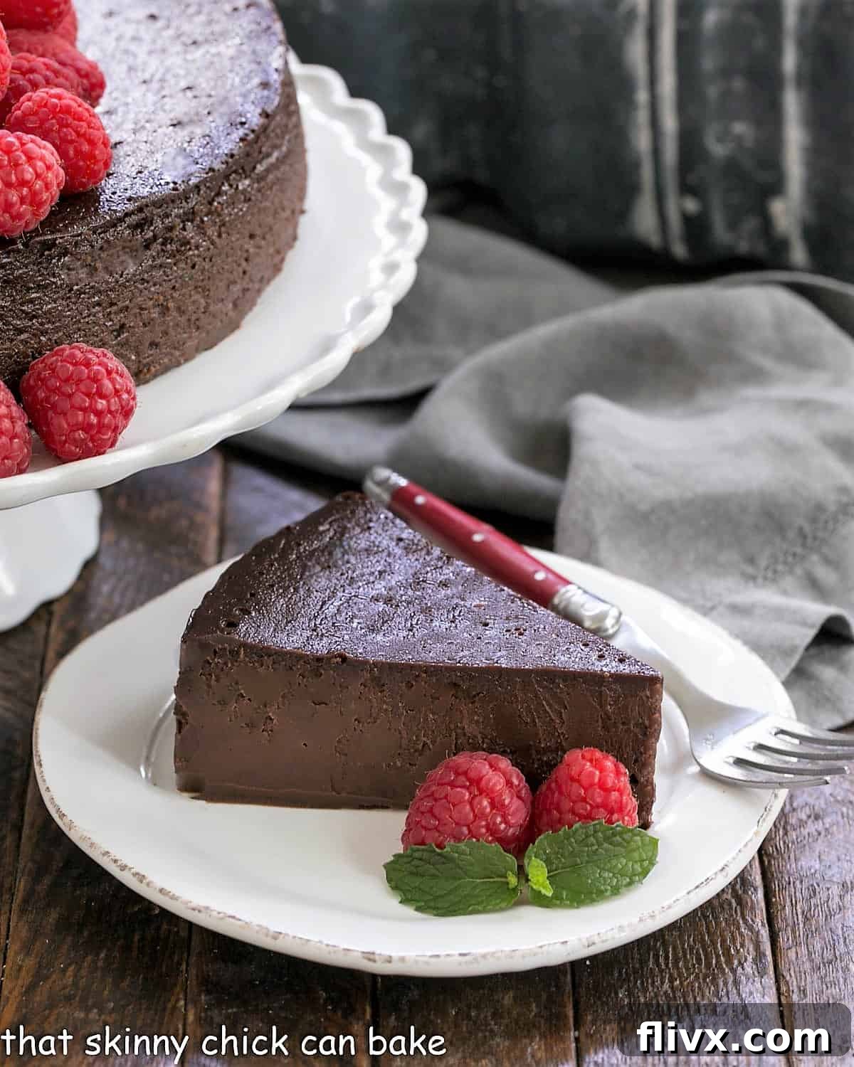 A perfectly sliced Flourless Chocolate Kahlua Cake resting next to the full cake on an elegant cake stand, highlighting its rich, dark interior and moist texture.