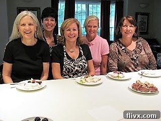A group of friends happily sampling their freshly made mini pavlovas in a home kitchen setting