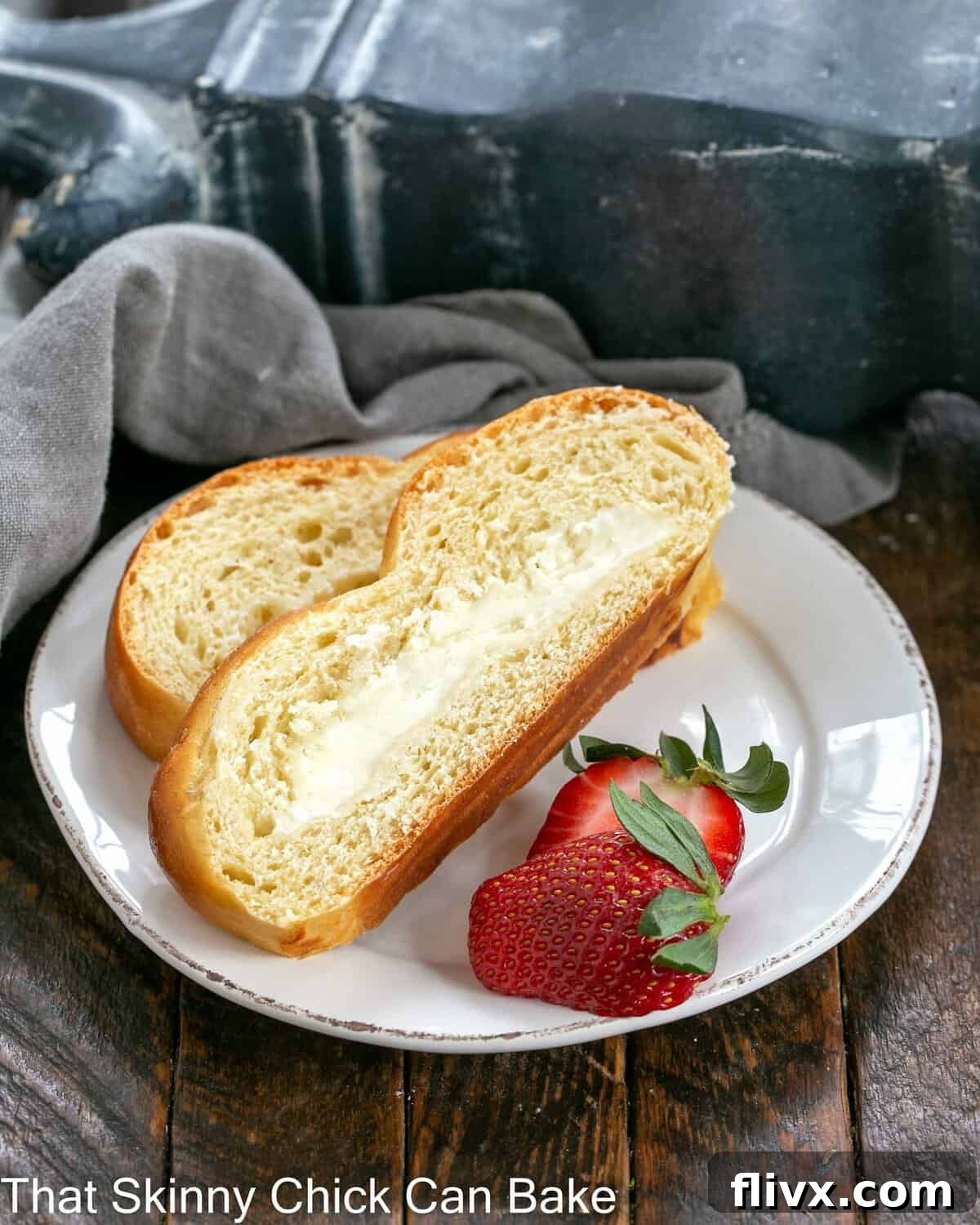 Two slices of braided Easter bread with strawberry garnish on a white plate.