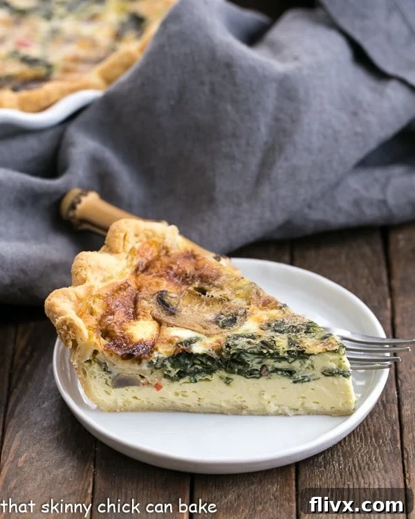 A vibrant slice of Spinach Mushroom Quiche on a pristine white plate, showcasing its golden crust and creamy, vegetable-filled interior.