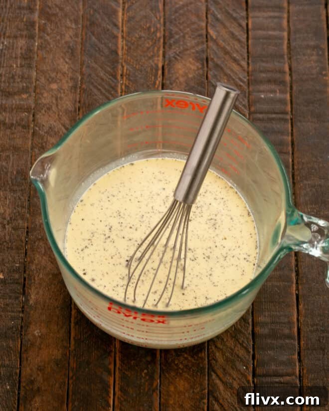 Ingredients for quiche custard, including eggs, half-and-half, and heavy cream, being whisked in a bowl.