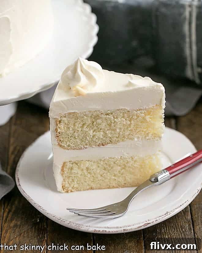 Perfect slice of Classic White Layer Cake with White Chocolate Swiss Meringue Buttercream, elegantly presented on a white dessert plate.