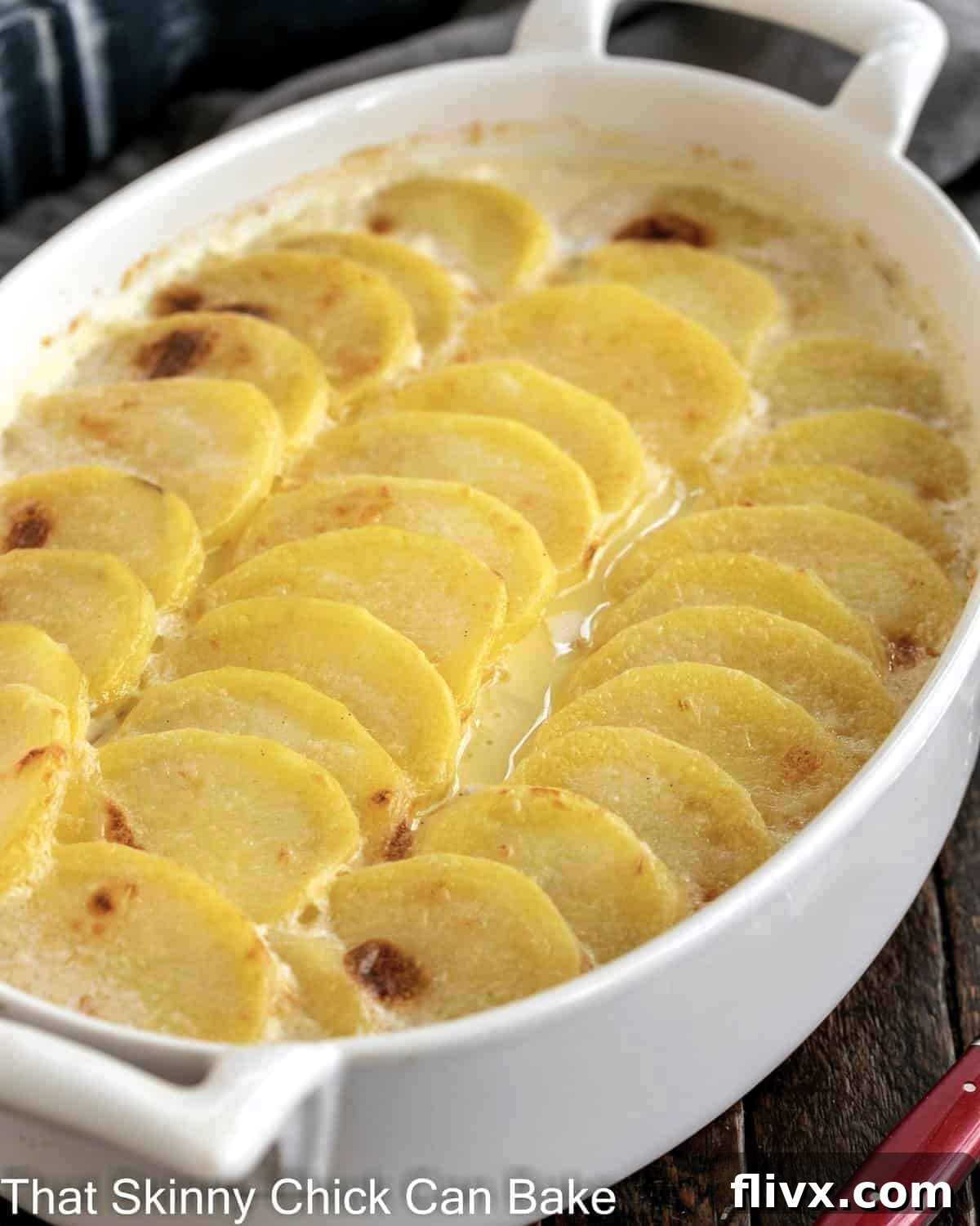 Oval casserole dish of perfectly baked scalloped potatoes, golden brown and bubbling.
