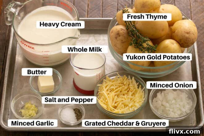 Scalloped Potatoes ingredients on a metal sheet pan with labels, including potatoes, cheeses, and herbs.