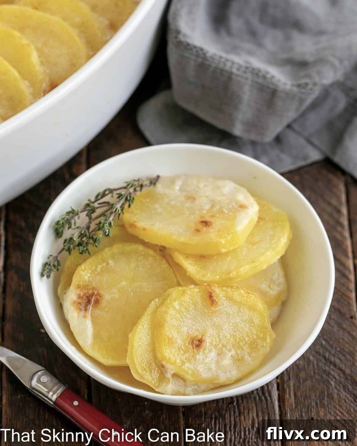 Close-up view of a small bowl of scalloped potatoes next to the casserole dish, showcasing the cheesy layers.