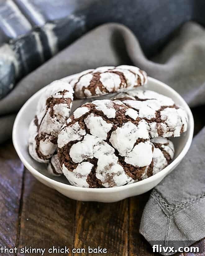 Fudgy Chocolate Earthquake Cookies arranged beautifully in a white ceramic bowl, showcasing their rich color and snowy cracks.