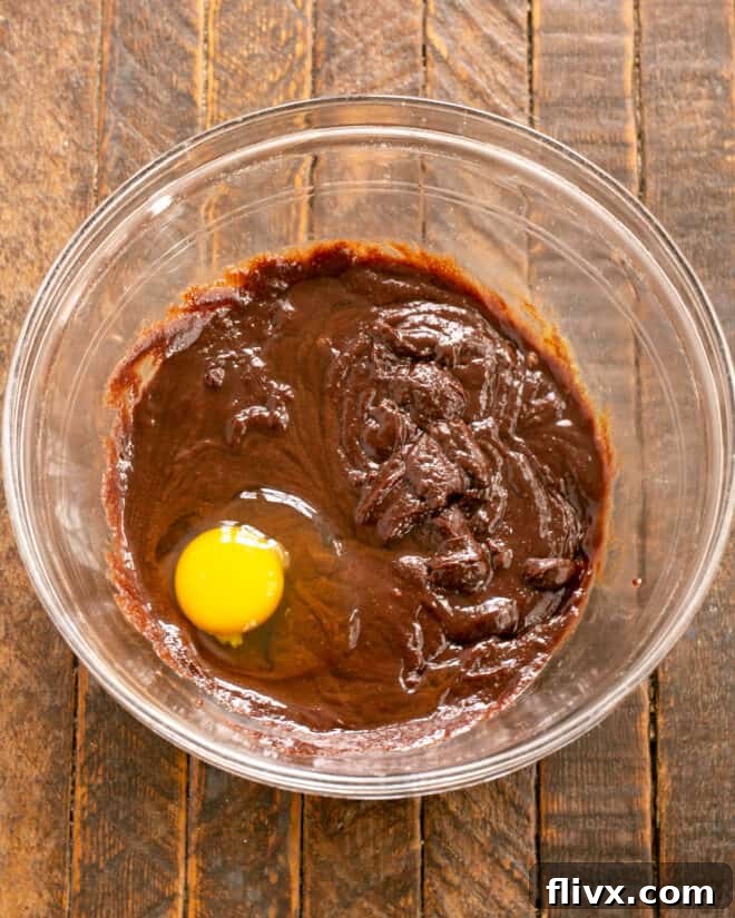 Earthquake Cookies Step 4: Incorporating eggs into the chocolate mixture using a hand mixer.