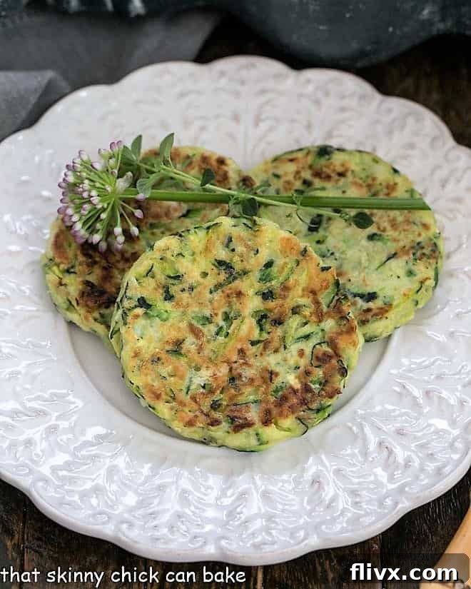 Overhead view of 3 zucchini fritter on a fancy, decorative white plate.