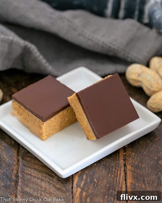 A pair of perfectly sliced Better Than Reese's Peanut Butter Bars showcased on a square white plate, highlighting their layers.