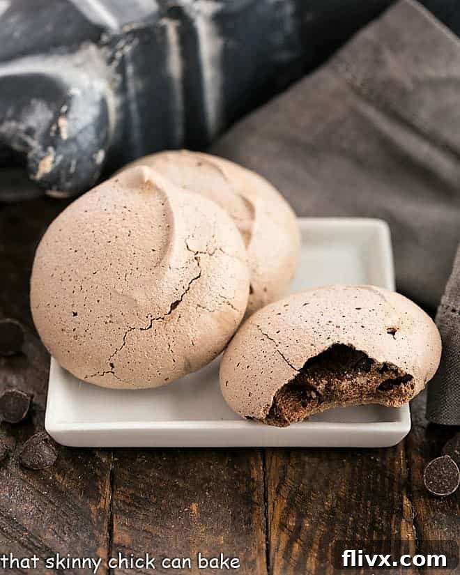 Three delicious chocolate meringues, two whole and one with a bite taken out, revealing its chewy, chocolatey center.