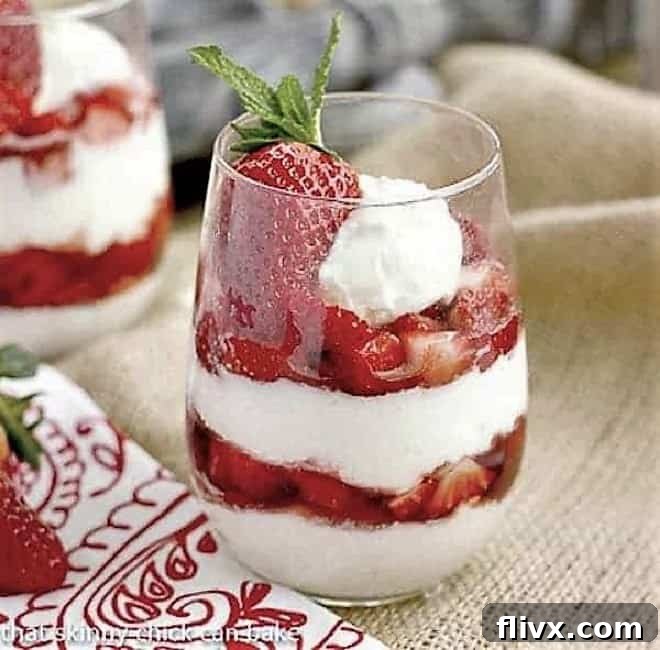 No-Bake Strawberry Cheesecake Parfaits layered in clear drinking glasses, garnished with a whole strawberry.