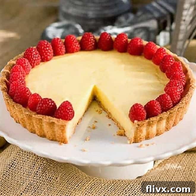 A stunning French Lemon Tart, Tarte au Citron, proudly displayed on a cake stand with one slice already removed, revealing its luscious lemon filling.