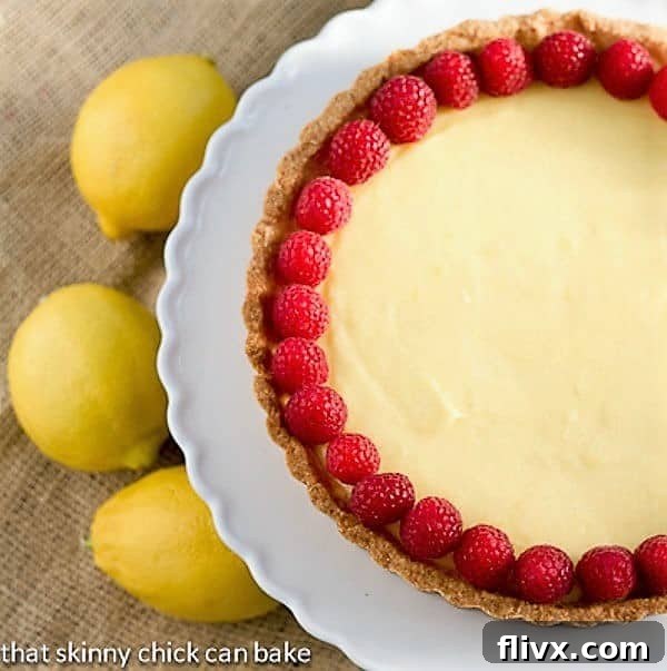 Close-up shot of a magnificent French Lemon Tart, adorned with fresh raspberries, highlighting its smooth, glossy lemon filling.