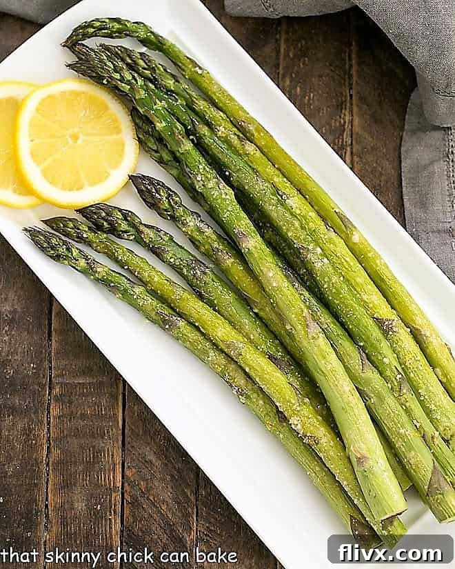 Overhead view of Easy Oven Roasted Asparagus on a white tray with lemon slices.