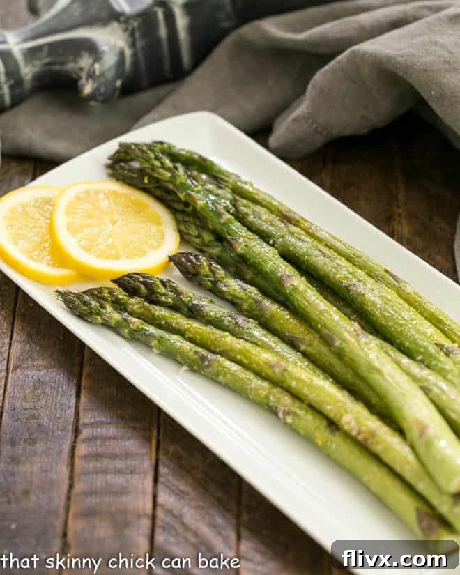 Easy Oven Roasted Asparagus on a white tray with lemon slices to garnish