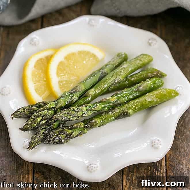Overhead view of Easy Oven Roasted Asparagus on a white plate with lemon slices