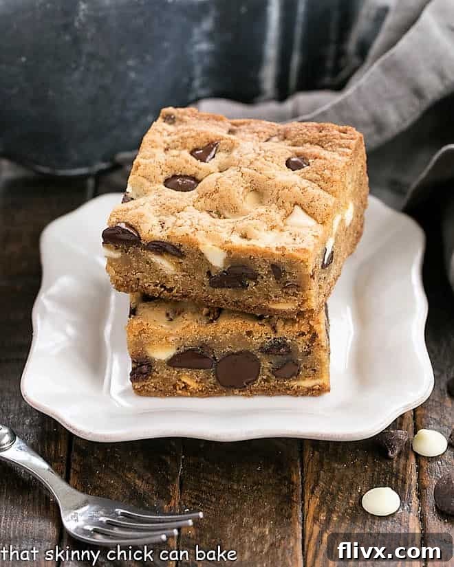 Two chocolate chip bars stacked on a decorative white dessert plate with an adjacent fork, ready to be enjoyed.
