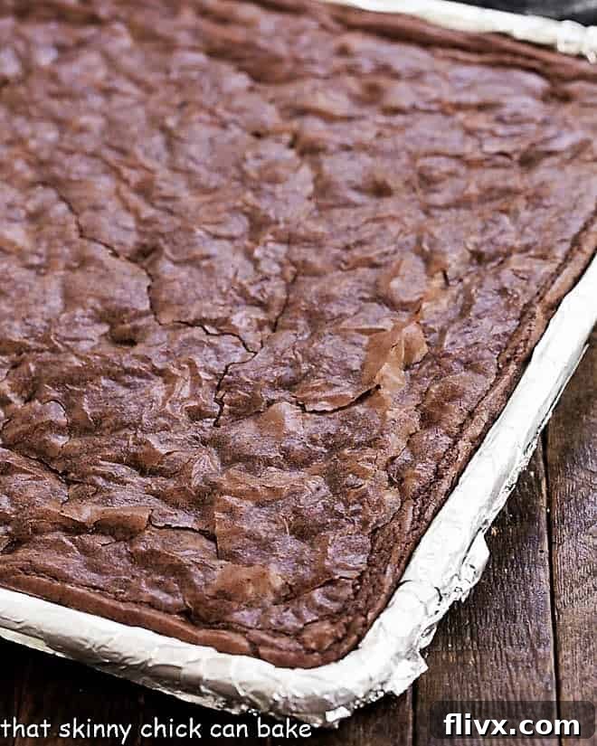 Sheet Pan Brownies in a baking sheet lined with non-stick foil, ready for cooling and cutting.