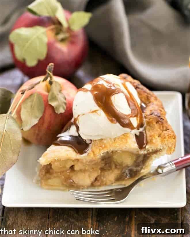 Caramel Apple Pie on a square white plate topped with ice cream and caramel sauce.